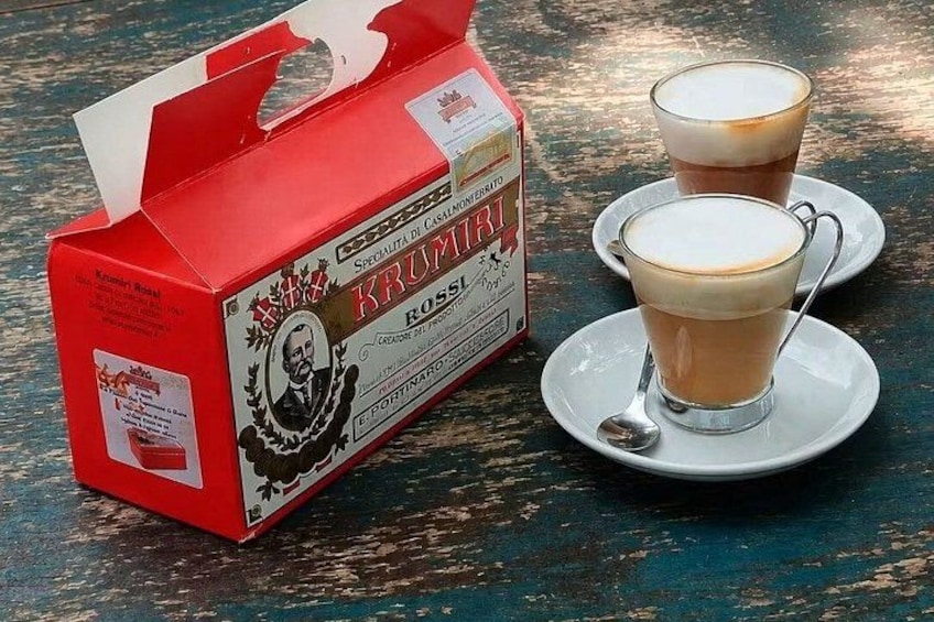 A red Krummel coffee box and two cups of coffee on saucers. 2