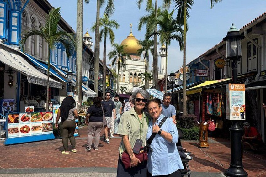 A street with people, palm trees, and a building with a golden dome. 5