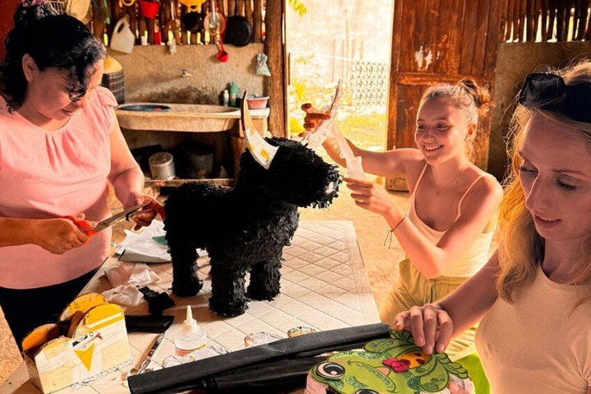 A person cutting a black dog's fur, with another person holding a drink and a third person observing. 1