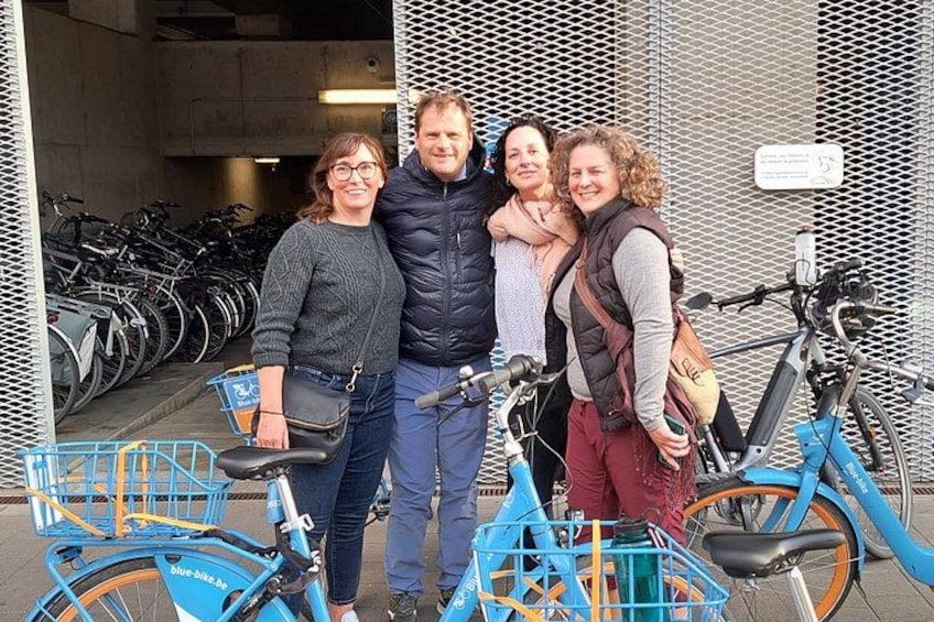 Four people standing in front of a bicycle rack with bicycles. 1