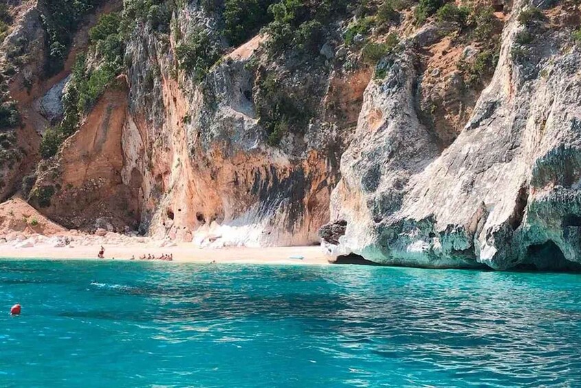 A coastal landscape with clear turquoise waters, rocky cliffs, and a sandy beach. 5