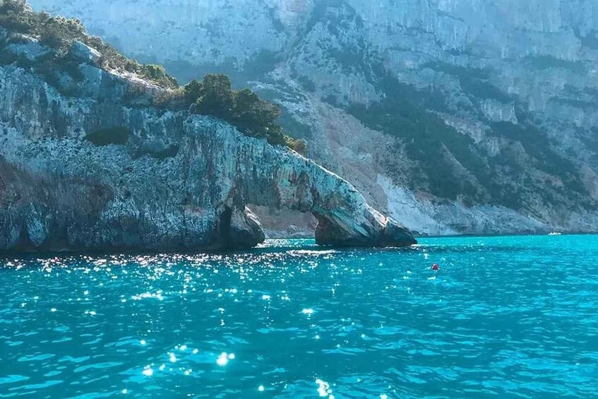 A coastal landscape with a rocky cliff and clear turquoise waters. 3