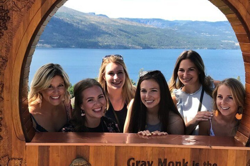 A group of people inside a wooden structure with a view of a lake and mountains. 5