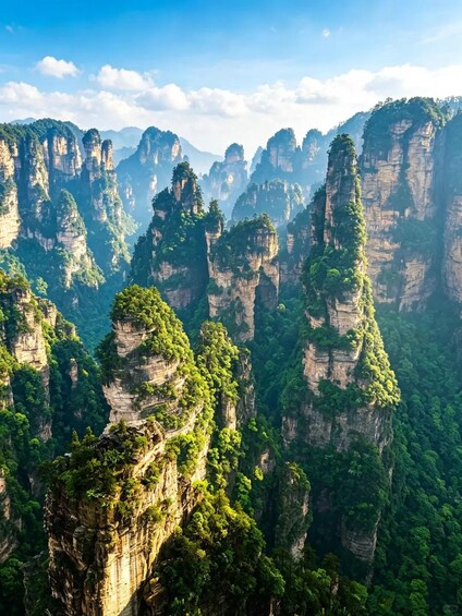 A landscape of towering limestone karst mountains with dense green vegetation. 2