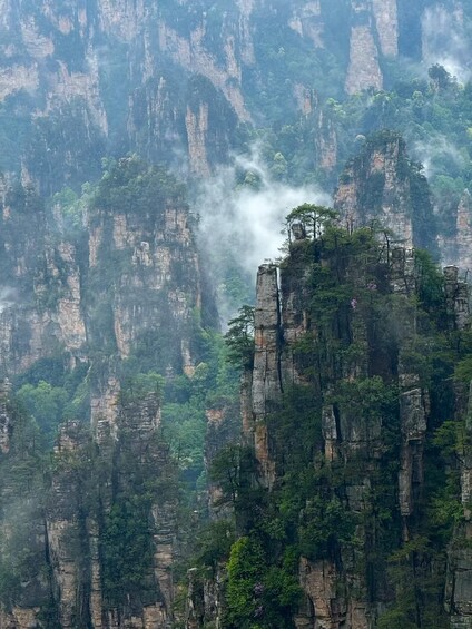 A mountainous landscape with towering rock formations and dense green vegetation. 1