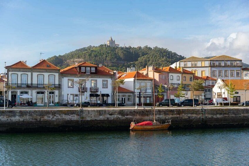 Una costa con edificios, un barco y una colina con un castillo al fondo. 4
