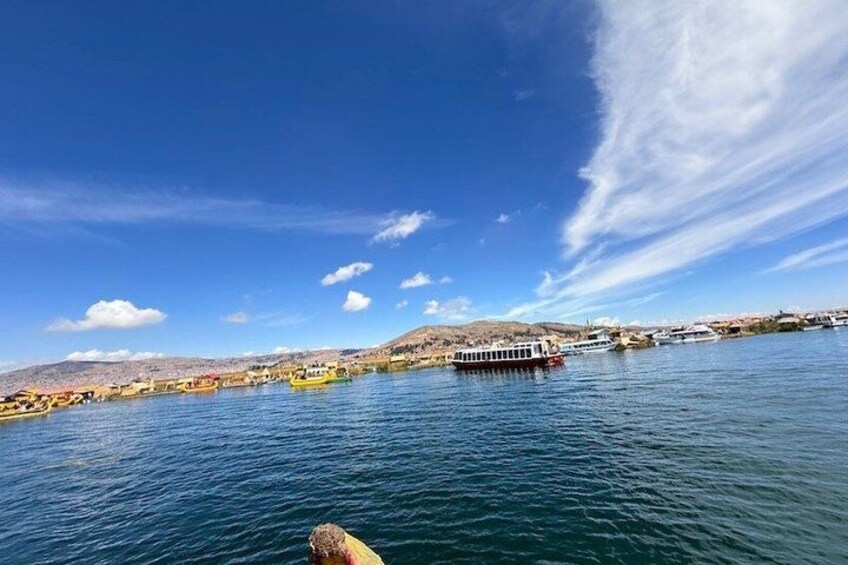 A river with boats, a clear sky, and a distant shoreline with buildings. 2