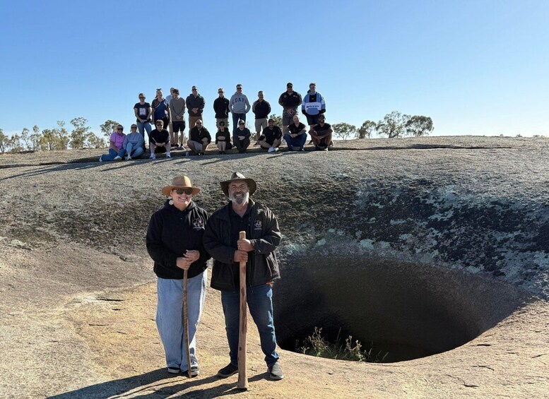 A group of people standing on a hill with a large hole in the ground. 1