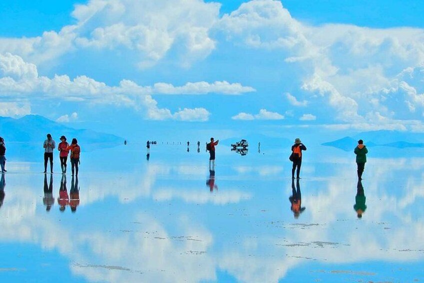 A group of people on a reflective surface with mountains in the background. 5