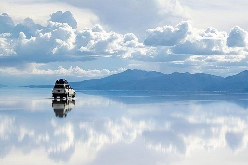 A white vehicle on a reflective water surface with mountains in the background. 4