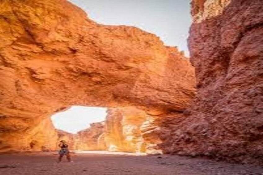 A person standing in a natural rock arch formation. 2