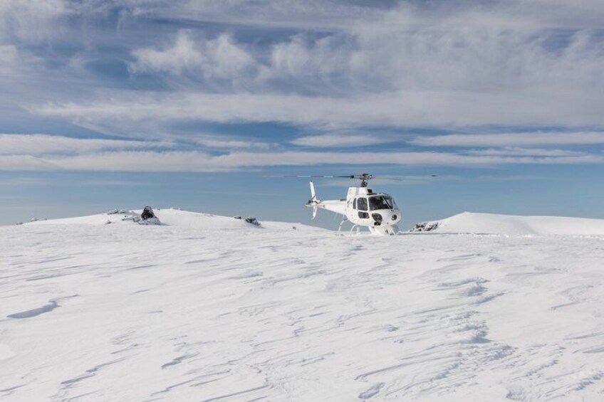 A white helicopter on a snowy landscape with a clear sky. 5