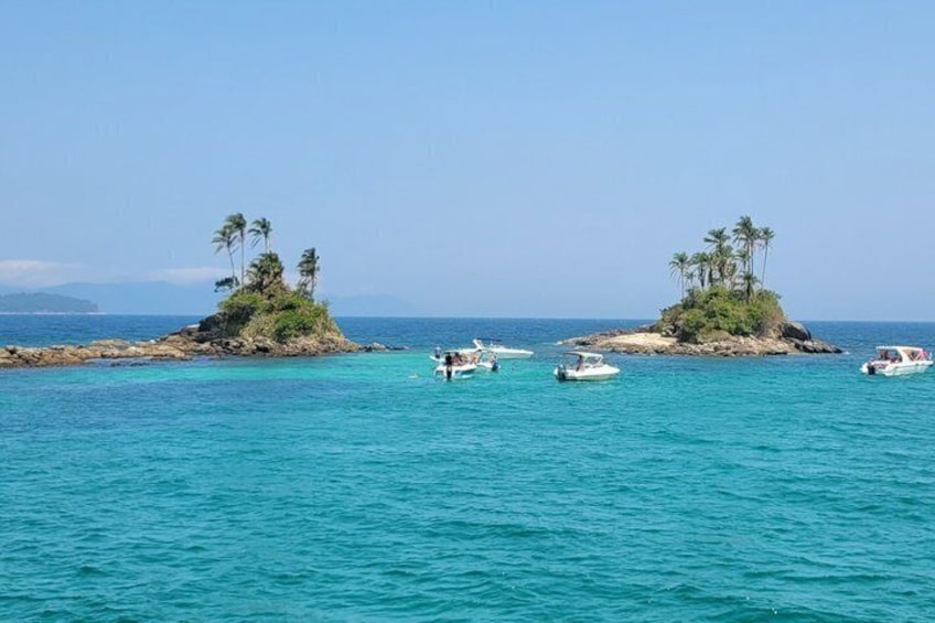 A turquoise sea with small islands, palm trees, and boats. 2