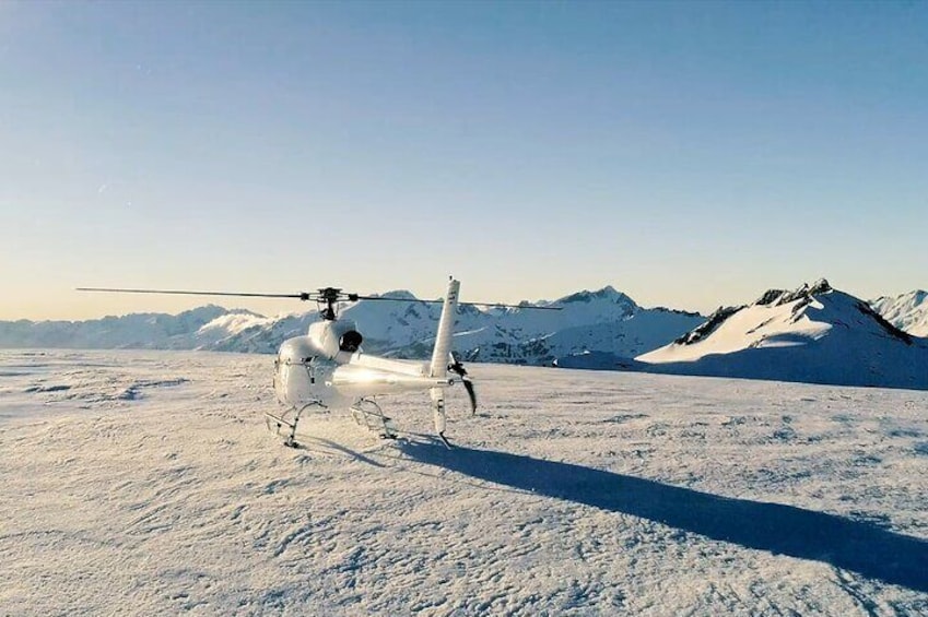 A white helicopter on a snowy mountain with a clear sky. 2