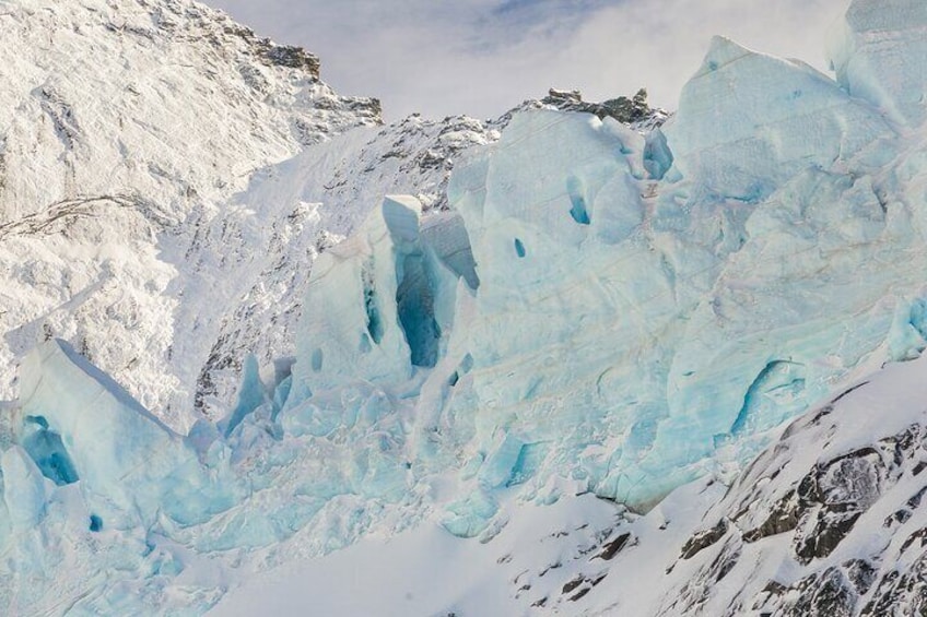 A glacier with ice formations and snow-covered mountains. 3