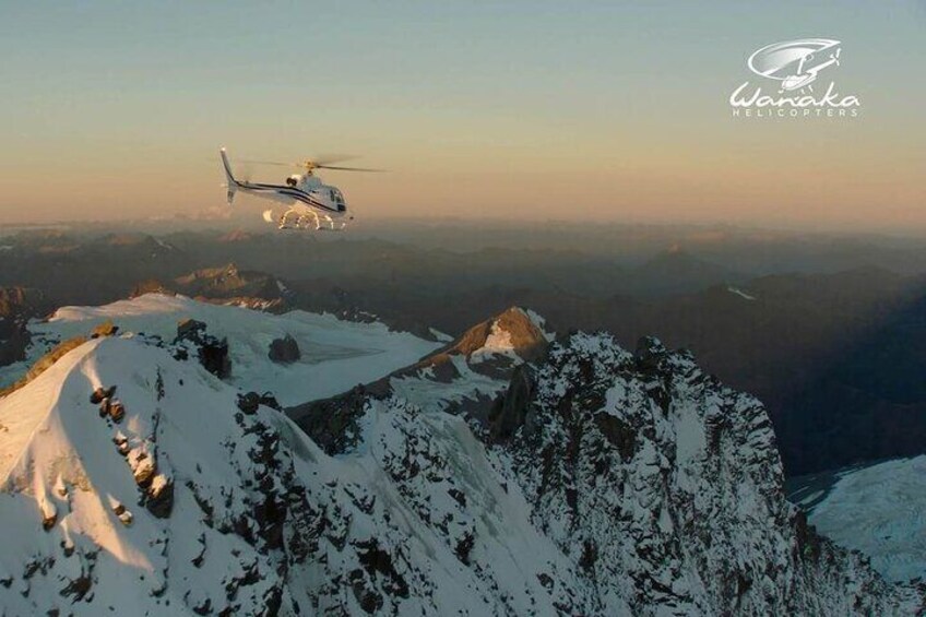 A helicopter flying over snow-covered mountains. 4