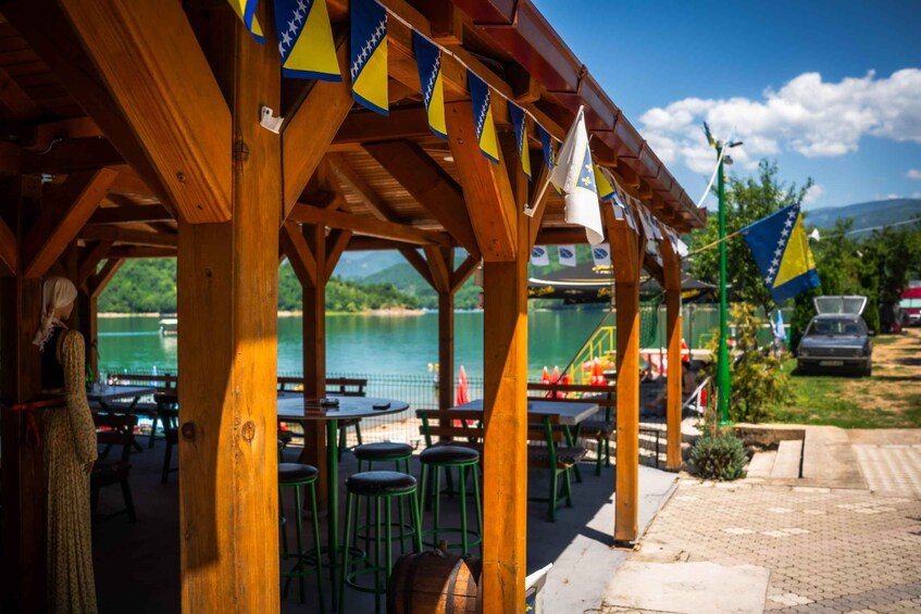 A wooden pavilion with tables and chairs, overlooking a body of water. 2