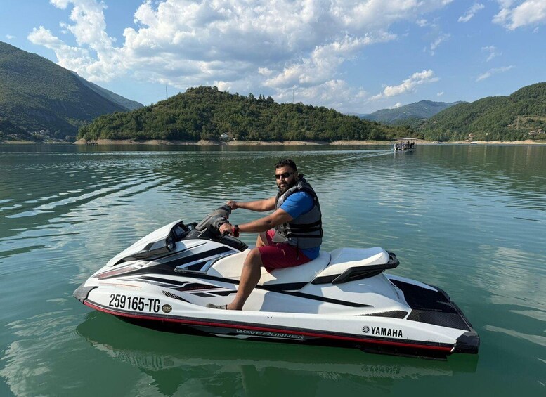 A person riding a Yamaha jet ski on calm water with mountains in the background. 4