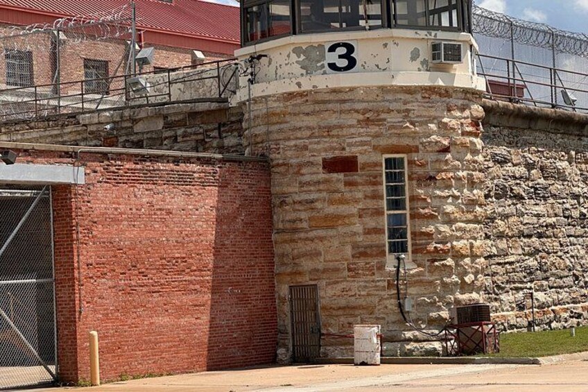 A stone building with the number 3, a metal gate, and a ladder leading to a window. 4