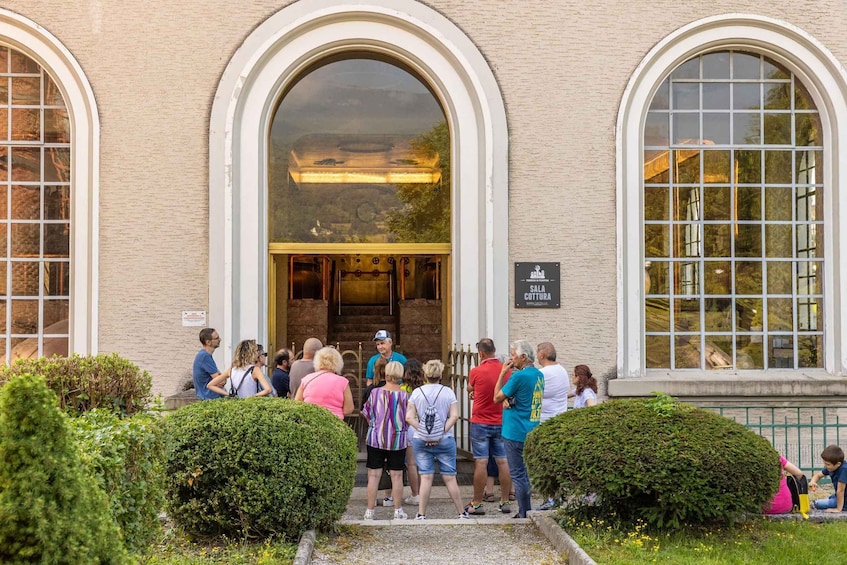 A group of people standing in front of a building with arched windows and a sign that reads "SALA COTTURA". 3