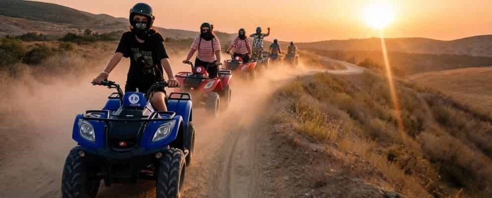 People riding ATVs on a dirt road during sunset. 3
