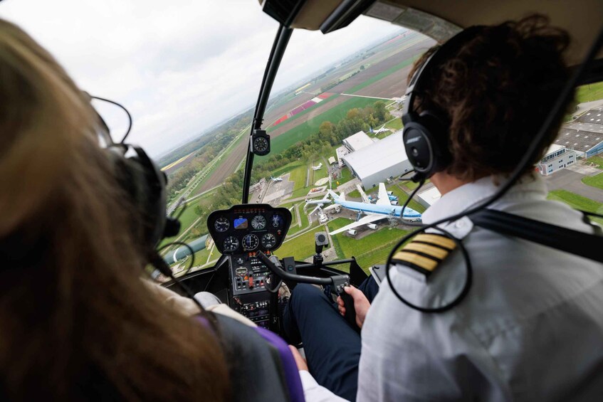 A helicopter cockpit with a view of a runway and airport buildings. 5