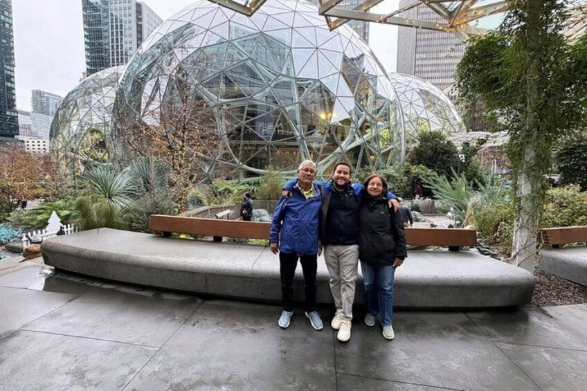 A group of people standing in front of a glass-domed structure with a garden in the background. 4