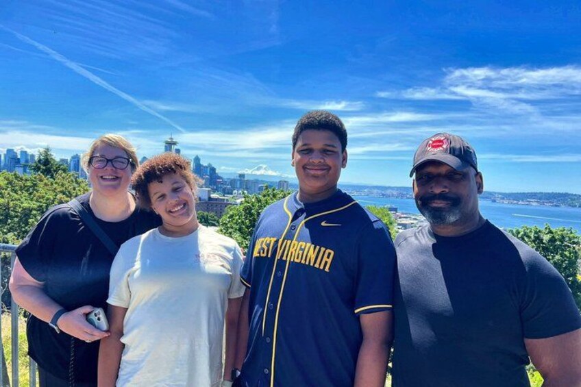 A group of people standing on a balcony with a city skyline and water in the background. 1