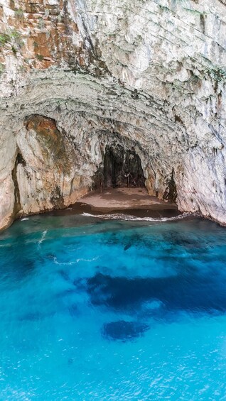 A natural cave opening with clear blue water at the bottom. 4
