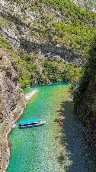 A turquoise river winding through a rocky gorge with a boat and kayaks. 3