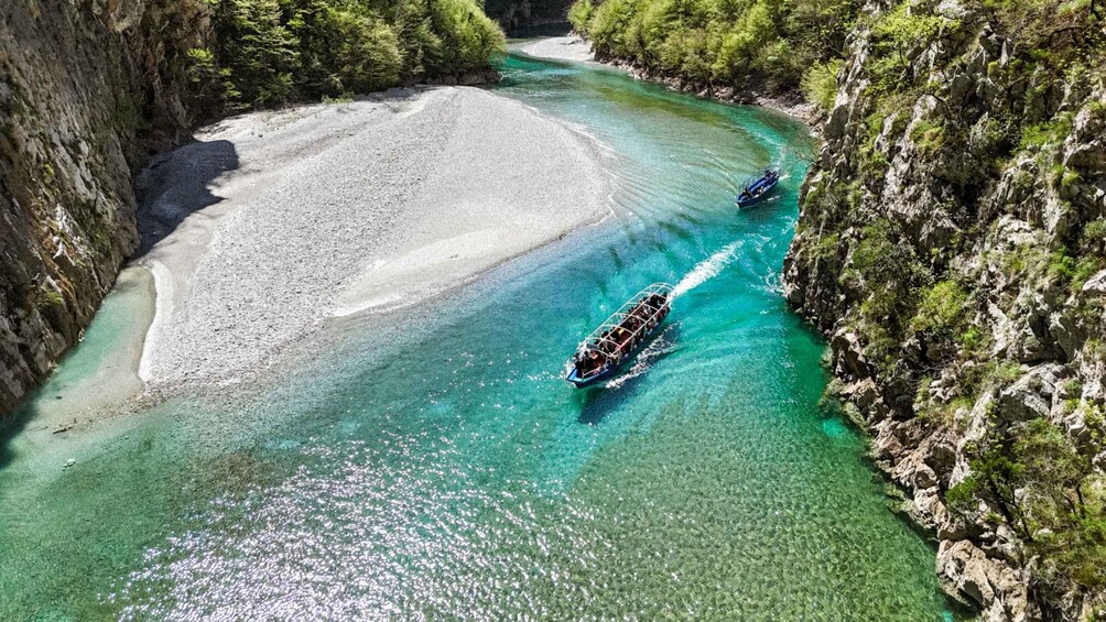 A river with clear turquoise water, surrounded by rocky cliffs and dense greenery. 2