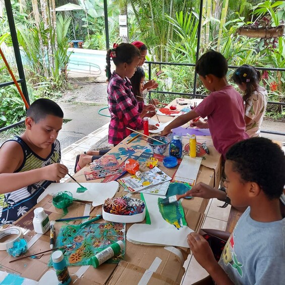 Kinder malen draußen mit verschiedenen Malutensilien an einem Tisch. 2