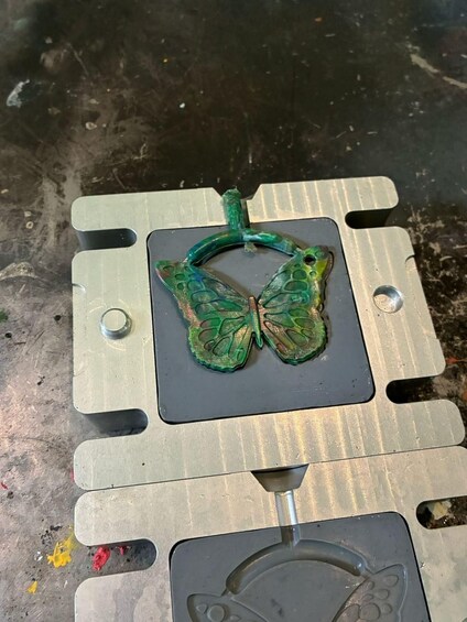 Ein metallisches Objekt mit einer schmetterlingsförmigen Form auf einer Werkbank. 4