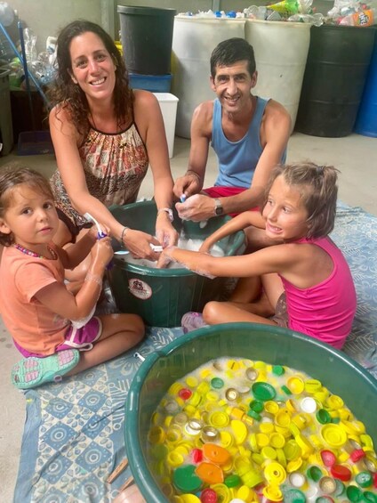 Eine vierköpfige Familie ist bei einer Bastelarbeit mit bunten Plastikdeckeln beschäftigt. 5