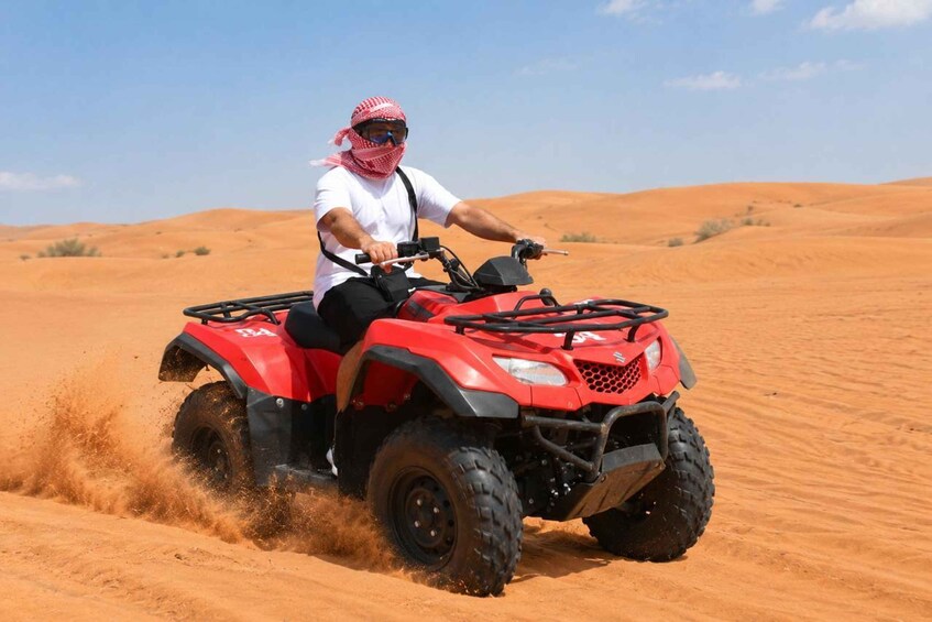 A person riding a red ATV in a desert with sand dunes. 4
