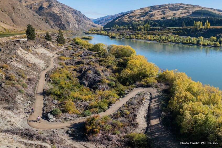 A winding mountain trail with a lake and forested hills in the background. 2