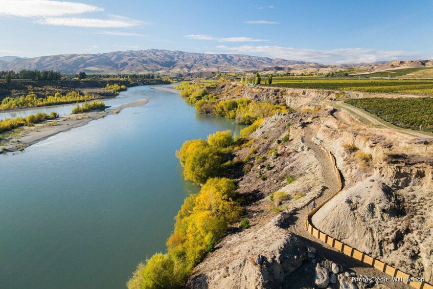 A river winding through a valley with a dirt path alongside. 3