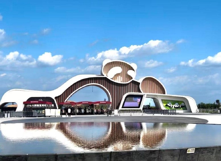 A modern building with unique architecture, a reflective water feature in front, and a clear blue sky. 1