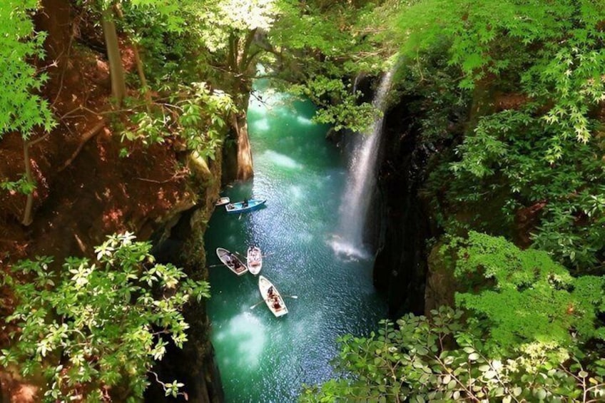 A river with kayaks, surrounded by dense forest and a waterfall. 3