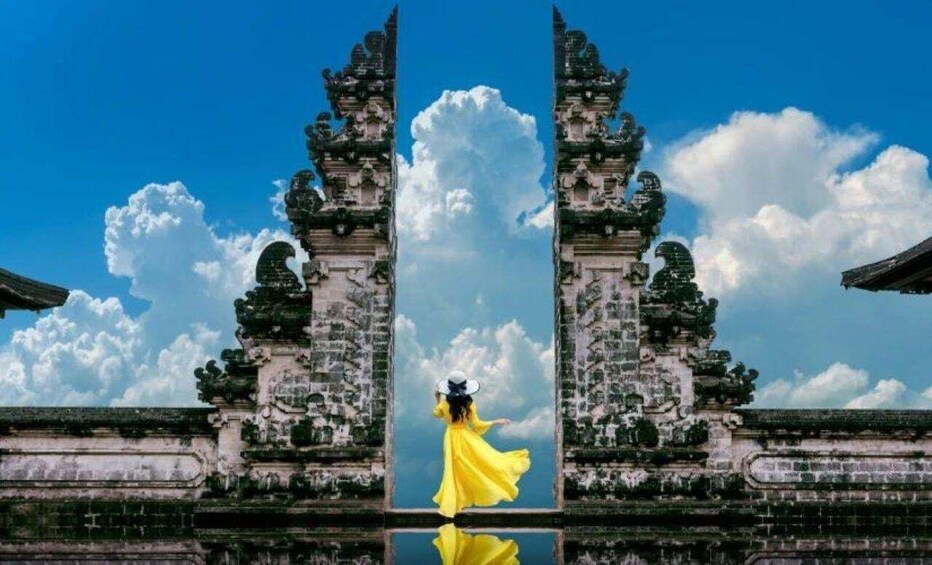A symmetrical architectural structure with ornate carvings, a clear blue sky, and a reflective water surface. 1