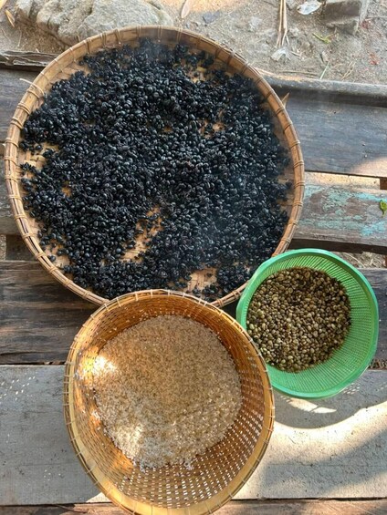 A wooden table with three baskets filled with different types of beans. 3