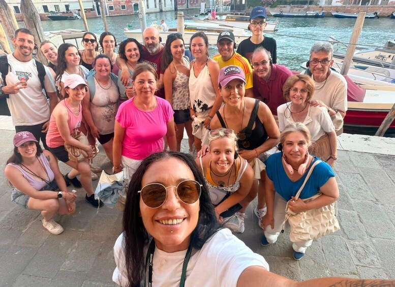 A group of people posing for a photo by a waterfront with boats and buildings in the background. 5