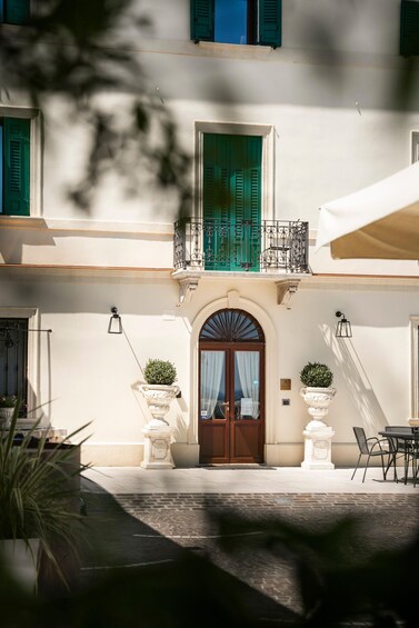 A building with a white facade, green shutters, and a wooden door. 4