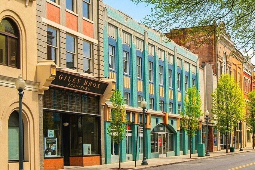 A street with colorful buildings, including a furniture store named Giles Bros. 1
