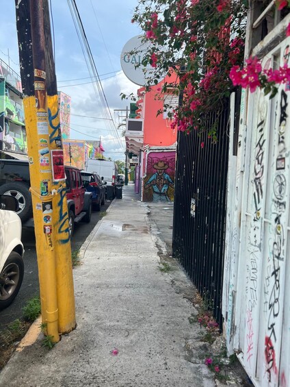 A narrow alley with parked cars, graffiti on walls, and a satellite dish on a building. 5