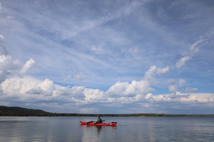 A calm lake with a kayaker in a red kayak. 3