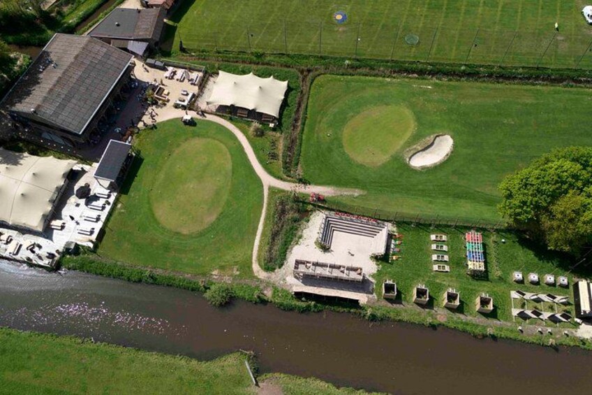 An aerial view of a golf course with bunkers, a clubhouse, and a river. 3