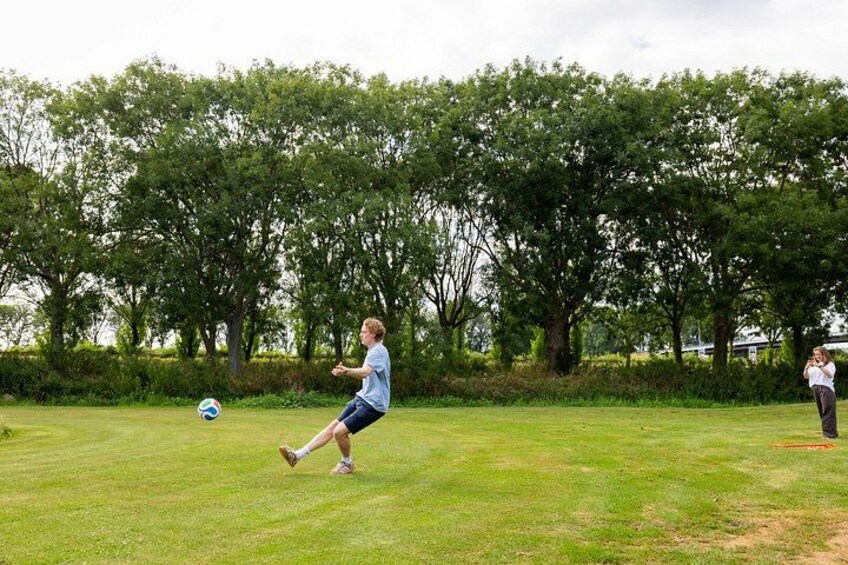 A person playing soccer on a grassy field with trees in the background. 4