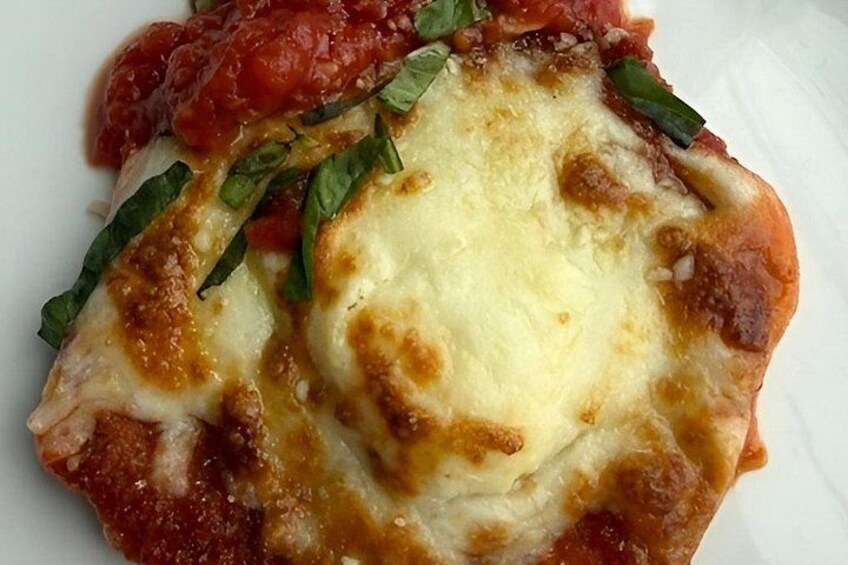 A close-up of a pizza with melted cheese and tomato sauce, garnished with basil leaves. 5