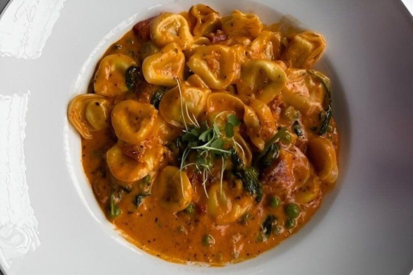 A plate of ravioli in a creamy tomato sauce, garnished with herbs. 4